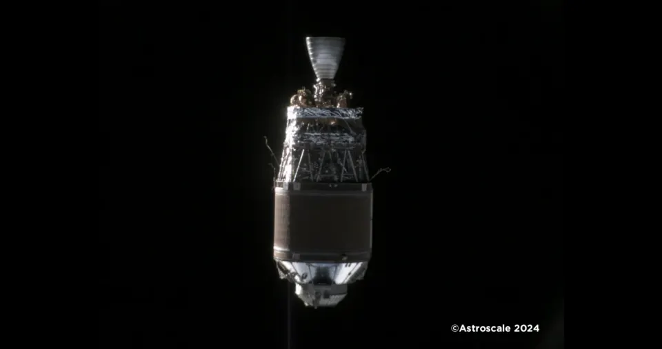 真っ暗な宇宙空間に浮かぶ、焦げ茶色の断熱材に包まれた円筒形のロケット上段。先端にエンジンのノズルが見える