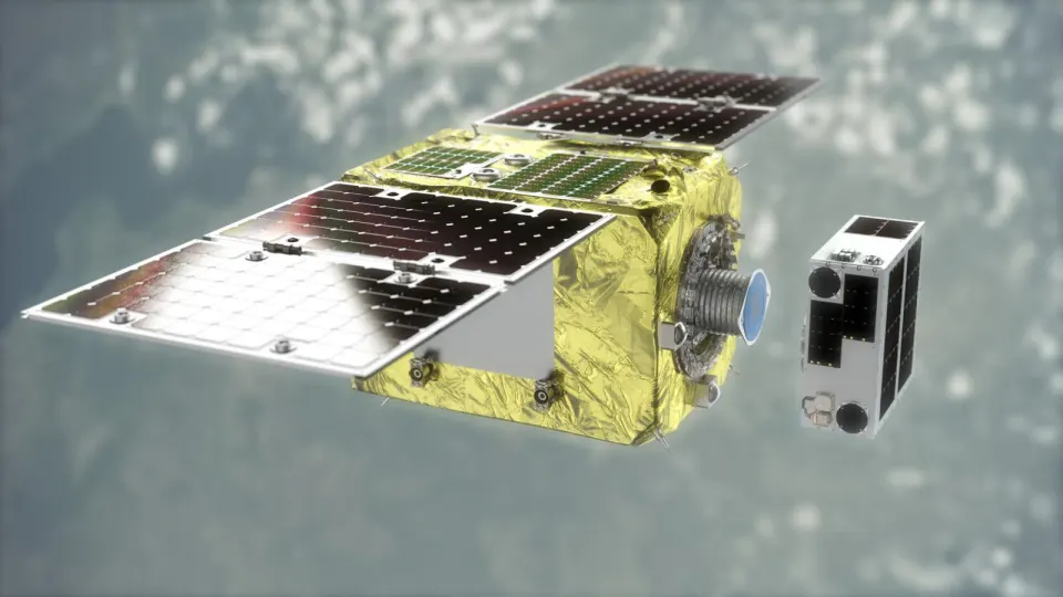 地球の上空で、金色の断熱材に包まれた箱型の衛星が、小さな白い衛星に近づいていくCG