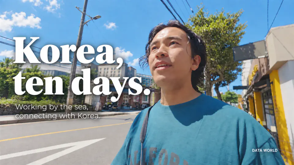 DATA WORLD editor-in-chief Kaito Ogasawara looking up at the sky on a street in Jeju. Text: Korea, ten days. Working by the sea, connecting with Korea